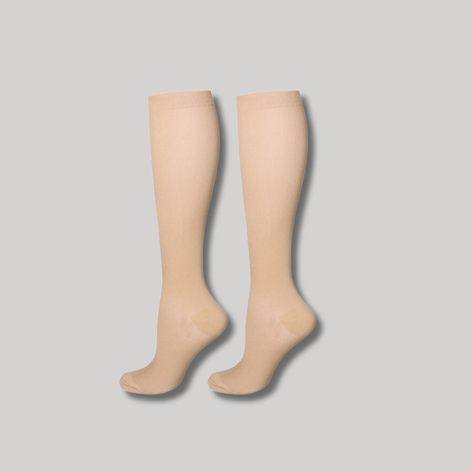 Ein Paar Tieberg™️ VitalSocks™ - Kompressionsstrümpfe für vitale Beine in beige, abgebildet nebeneinander auf hellgrauem Hintergrund mit nach links zeigenden Zehen.