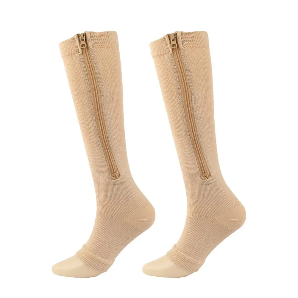 Ein Paar beige Tieberg™️ ZipperSocks - Kompressionsstrümpfe mit Reißverschluss, mit seitlichen Reißverschlüssen, abgebildet auf weißem Hintergrund.